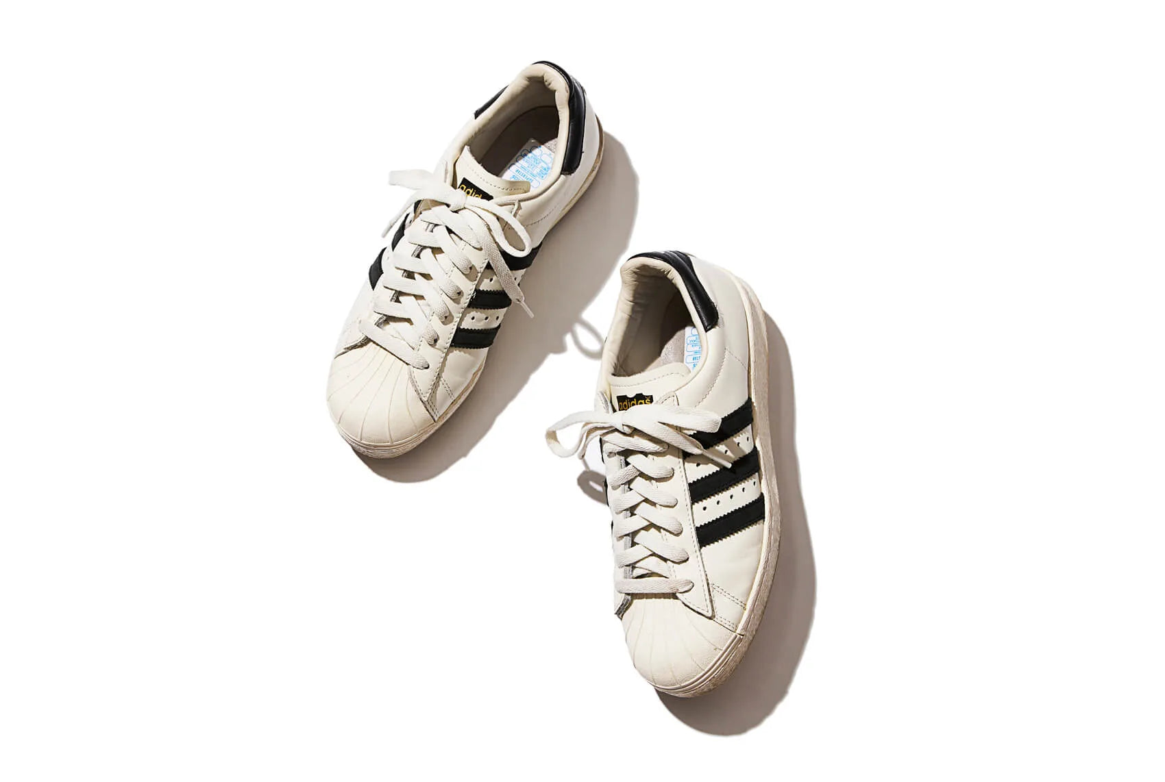 A pair of white Adidas sneakers with stripped on side