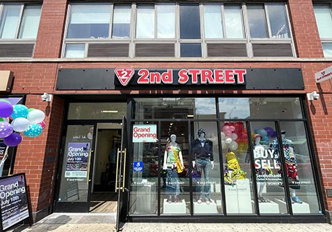 2nd Street clothing store storefront on a brick building, with large glass windows, mannequins inside, balloons, and grand opening signage.