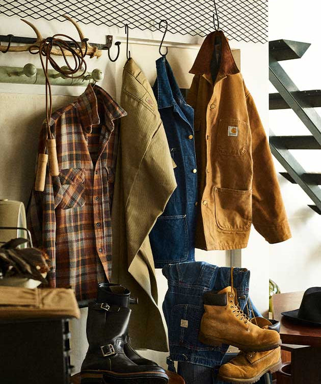 Clothing and boots hanging on a rack with a staircase in the background