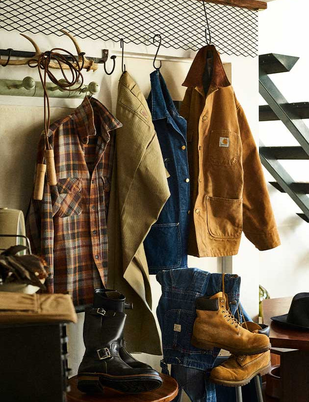 Clothing and boots hanging on a rack with a staircase in the background