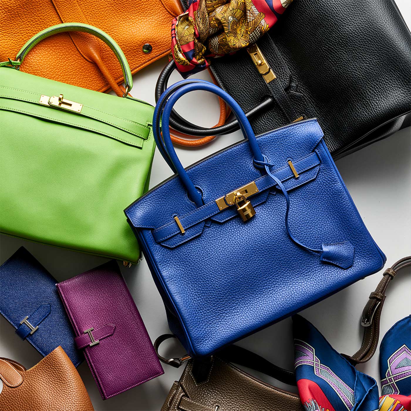 Collection of colorful handbags and wallets on a white surface