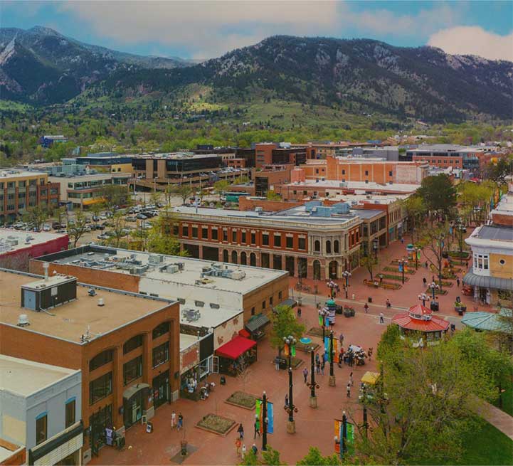 Town square with buildings and people, surrounded by mountains